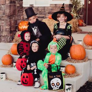 Image of people in Halloween costumes sitting amongst jack o lanterns