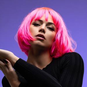 Image of a woman wearing a neon pink bob style costume wig with fringe.