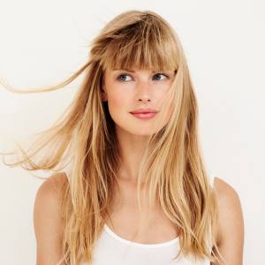 Image of a woman wearing a wind swept blonde costume wig with fringe.