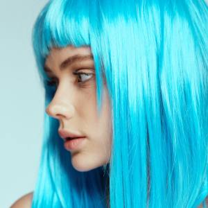 Close up image of a woman wearing a bright blue costume wig.