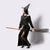Image of a woman dressed as a witch riding a wooden witch broom prop.