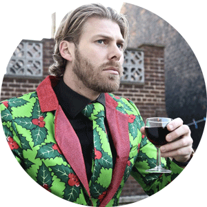 Image of a Man Wearing a Holly Print Christmas Suit and Holding a Glass of Wine