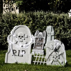 Image of 4 different outdoor grave stone Halloween decorations in a front yard.
