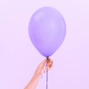 Image of a hand holding a single purple balloon.