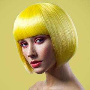 Image of a woman wearing a short bright yellow bob with a fringe.
